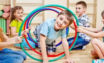Kid smiling while crawling though hoola hoops